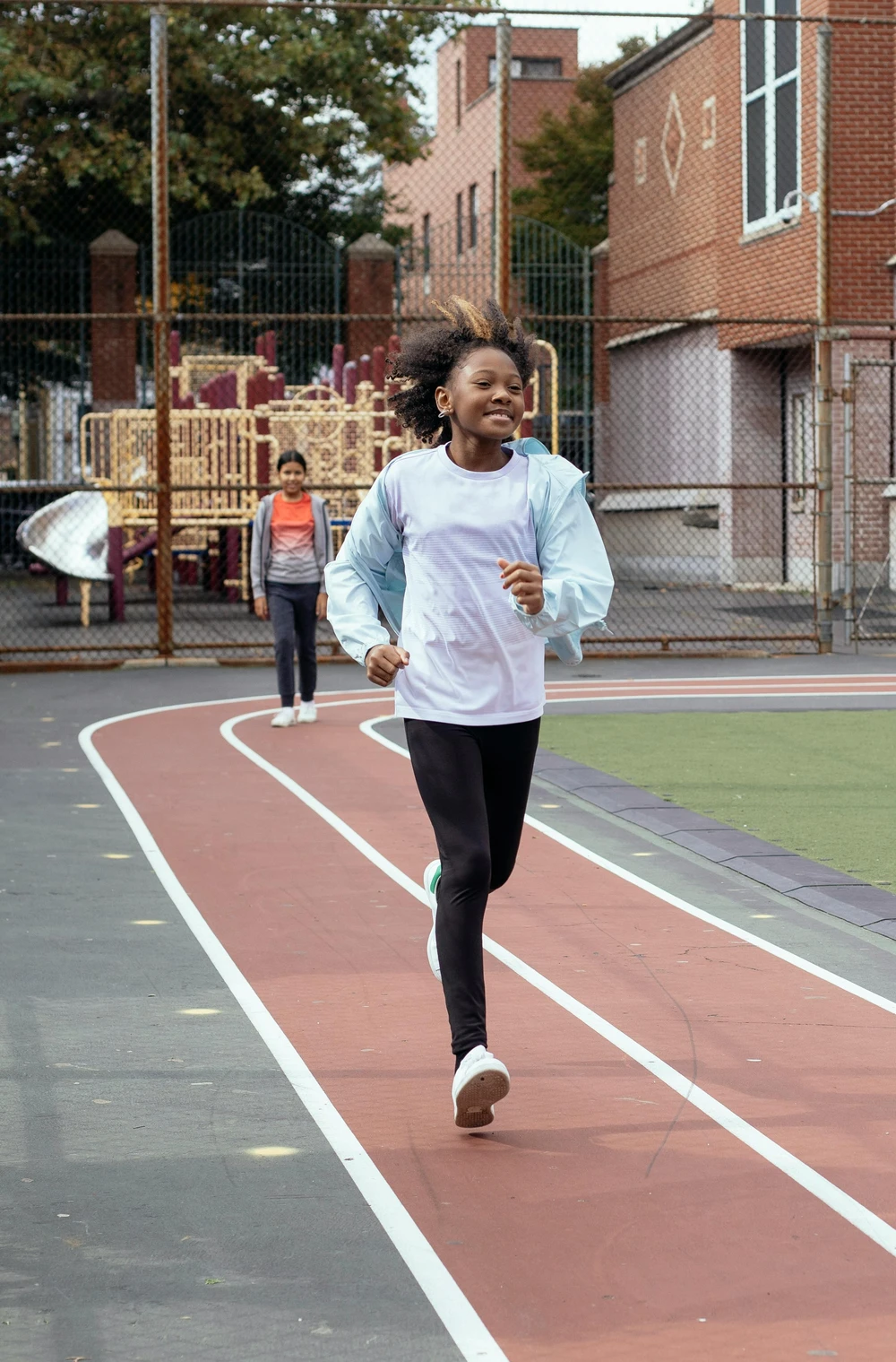 A Black girl is running on the school playground.